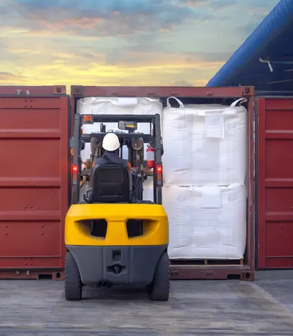 Gabelstapler hebt Big Bag in oder aus einem Container.